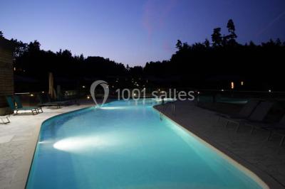 Lavabo avec plan en bois, sèche-serviettes mural, douche avec paroi vitrée et carrelage sombre.
