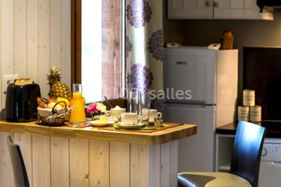 Lavabo avec plan en bois, sèche-serviettes mural, douche avec paroi vitrée et carrelage sombre.