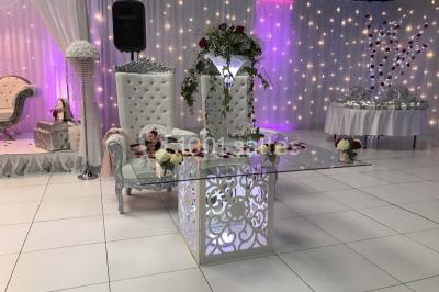 Salle de conférence avec des rangées de chaises vides, éclairée par des guirlandes lumineuses sur les murs.