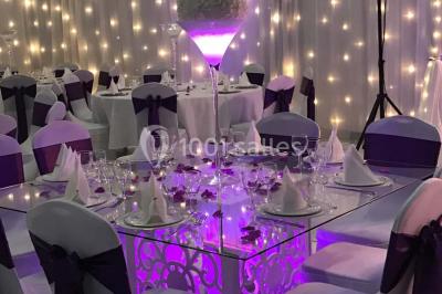 Salle de conférence avec des rangées de chaises vides, éclairée par des guirlandes lumineuses sur les murs.