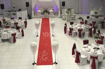 Salle de conférence avec des rangées de chaises vides, éclairée par des guirlandes lumineuses sur les murs.