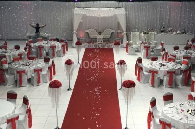 Salle de conférence avec des rangées de chaises vides, éclairée par des guirlandes lumineuses sur les murs.