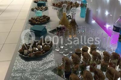 Salle de conférence avec des rangées de chaises vides, éclairée par des guirlandes lumineuses sur les murs.