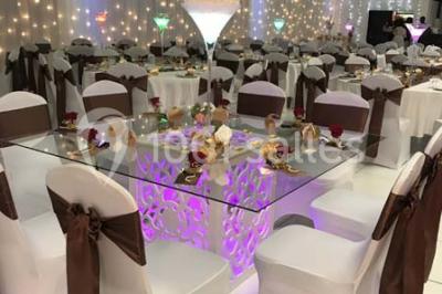 Salle de conférence avec des rangées de chaises vides, éclairée par des guirlandes lumineuses sur les murs.