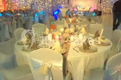 Salle de conférence avec des rangées de chaises vides, éclairée par des guirlandes lumineuses sur les murs.