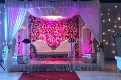 Salle de conférence avec des rangées de chaises vides, éclairée par des guirlandes lumineuses sur les murs.