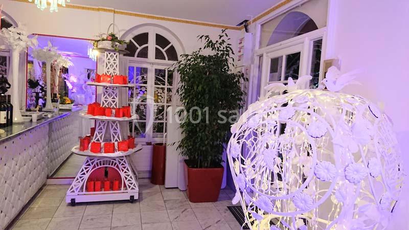 Décoration intérieure avec une tour Eiffel blanche portant des boîtes rouges, près d'une plante et d'une lampe ornée de…