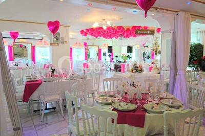 Décoration intérieure avec comptoir en marbre, plantes, ballons dorés et blancs disposés sur une structure décorative.