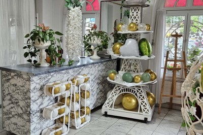 Décoration intérieure avec comptoir en marbre, plantes, ballons dorés et blancs disposés sur une structure décorative.