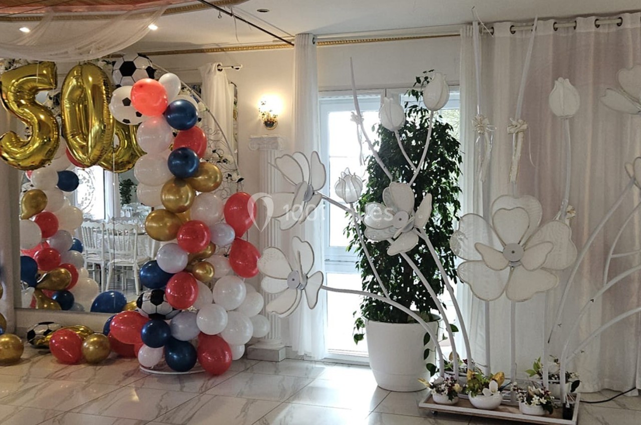 Location salle Athis-Mons (Essonne) - La Bella Vita #35 Décoration festive avec ballons colorés et chiffres dorés ’50’ dans une salle ornée de rideaux et plantes.