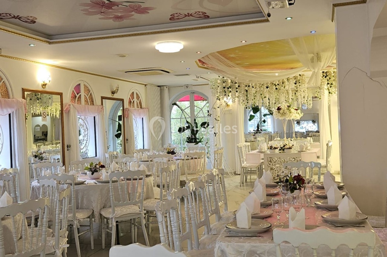Location salle Athis-Mons (Essonne) - La Bella Vita #2 Salle de réception lumineuse décorée de fleurs blanches, tables dressées avec nappes blanches et chaises élégantes.
