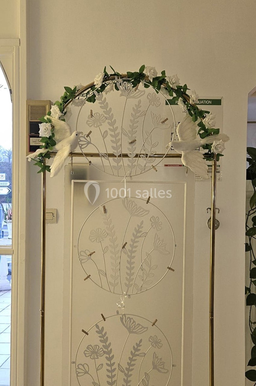 Location salle Athis-Mons (Essonne) - La Bella Vita #41 Arche décorative dorée ornée de fleurs blanches et de feuillage, placée devant un panneau floral blanc.