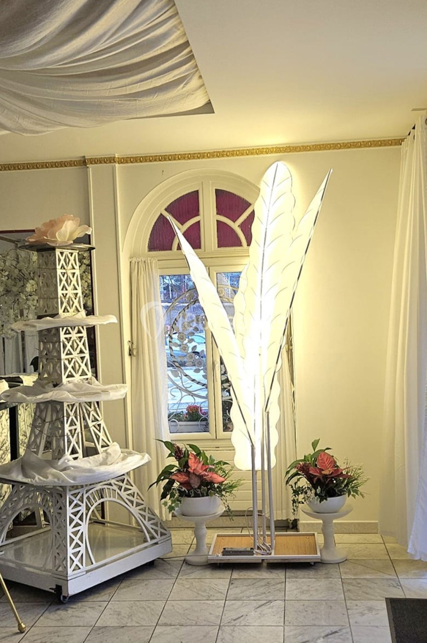 Location salle Athis-Mons (Essonne) - La Bella Vita #43 Lampadaire en forme de feuilles blanches éclairé, entouré de plantes et d'une décoration en forme de tour Eiffel blanche.