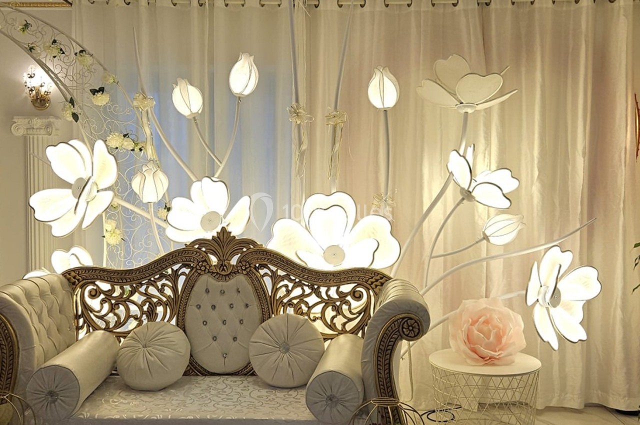 Location salle Athis-Mons (Essonne) - La Bella Vita #45 Canapé décoratif devant un rideau lumineux orné de fleurs blanches, dans un cadre élégant et raffiné.