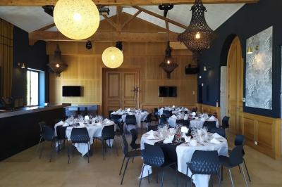 Salle avec un bar, tables hautes et éclairage violet, grandes fenêtres ouvertes sur une terrasse.