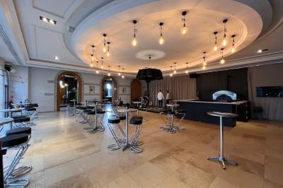 Salle avec un bar, tables hautes et éclairage violet, grandes fenêtres ouvertes sur une terrasse.