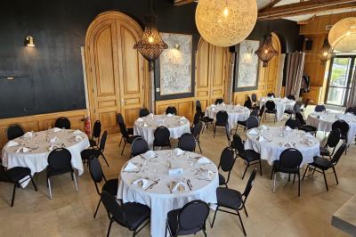 Salle avec un bar, tables hautes et éclairage violet, grandes fenêtres ouvertes sur une terrasse.