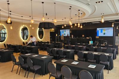 Salle avec un bar, tables hautes et éclairage violet, grandes fenêtres ouvertes sur une terrasse.
