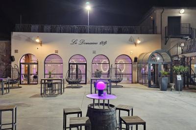 Salle avec un bar, tables hautes et éclairage violet, grandes fenêtres ouvertes sur une terrasse.