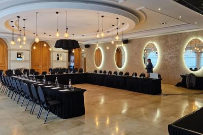 Salle avec un bar, tables hautes et éclairage violet, grandes fenêtres ouvertes sur une terrasse.