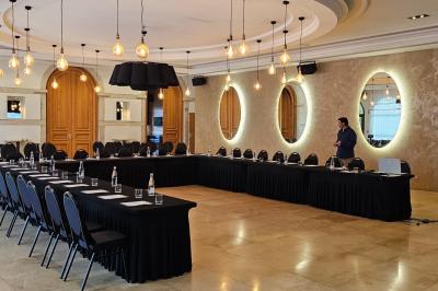 Salle avec un bar, tables hautes et éclairage violet, grandes fenêtres ouvertes sur une terrasse.