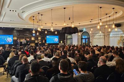 Salle avec un bar, tables hautes et éclairage violet, grandes fenêtres ouvertes sur une terrasse.