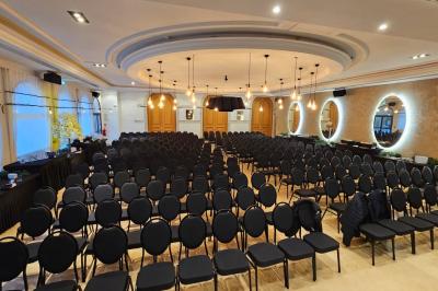 Salle avec un bar, tables hautes et éclairage violet, grandes fenêtres ouvertes sur une terrasse.