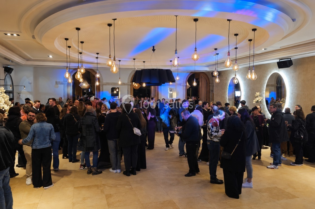 Groupe de personnes rassemblées dans une salle élégante avec éclairage chaleureux et décorations modernes.