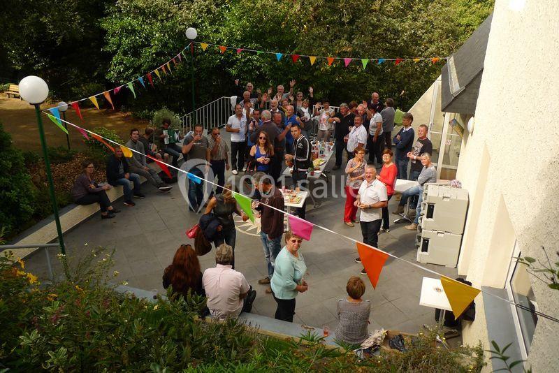 Groupe de personnes réunies sur une terrasse extérieure décorée de guirlandes colorées, lors d'un événement convivial.