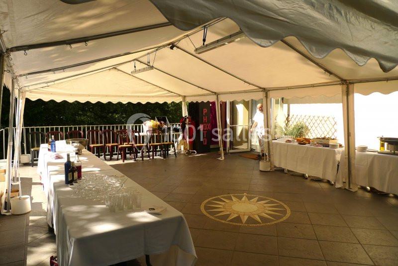 Tente blanche abritant des tables dressées pour un buffet, avec un photobooth en arrière-plan.