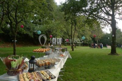 Cuisine professionnelle avec murs jaunes, plan de travail en inox, évier, cuisinière, fenêtre et équipements de rangement.