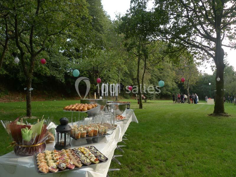 Buffet en plein air sur une table blanche, avec des arbres décorés de lanternes colorées en arrière-plan.