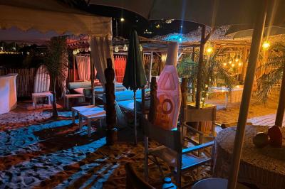 Bouteilles de vin rosé sur glace devant des parasols blancs et bleus sous un ciel dégagé.