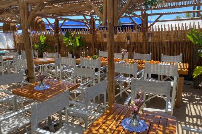 Bouteilles de vin rosé sur glace devant des parasols blancs et bleus sous un ciel dégagé.