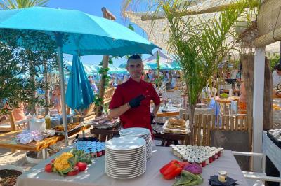 Bouteilles de vin rosé sur glace devant des parasols blancs et bleus sous un ciel dégagé.