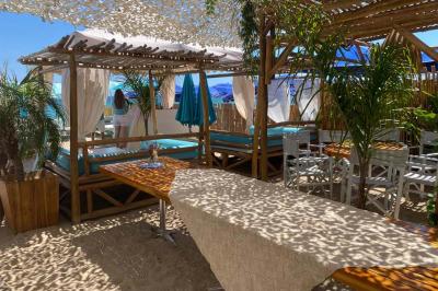 Bouteilles de vin rosé sur glace devant des parasols blancs et bleus sous un ciel dégagé.