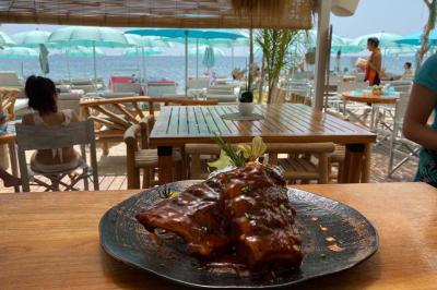 Bouteilles de vin rosé sur glace devant des parasols blancs et bleus sous un ciel dégagé.