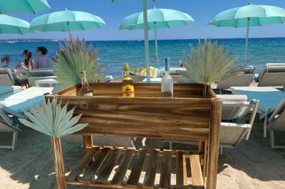 Bouteilles de vin rosé sur glace devant des parasols blancs et bleus sous un ciel dégagé.