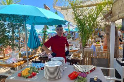 Bouteilles de vin rosé sur glace devant des parasols blancs et bleus sous un ciel dégagé.