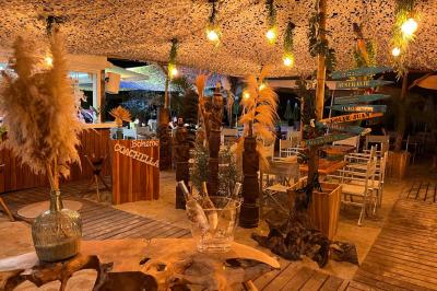Bouteilles de vin rosé sur glace devant des parasols blancs et bleus sous un ciel dégagé.