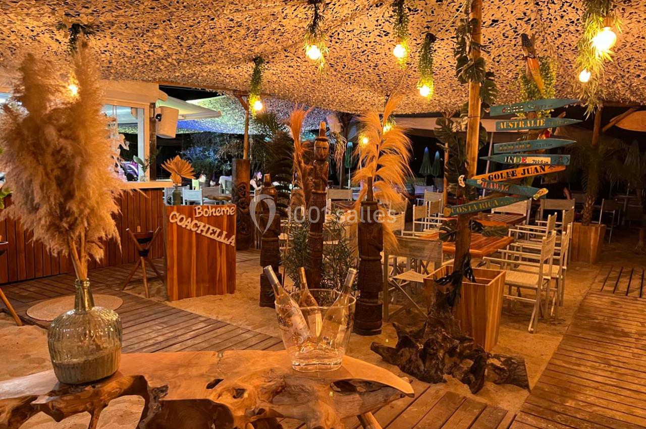 Décoration bohème avec plantes, lumières suspendues et mobilier en bois dans un espace extérieur chaleureux.