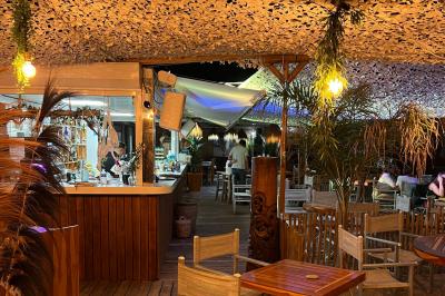 Bouteilles de vin rosé sur glace devant des parasols blancs et bleus sous un ciel dégagé.