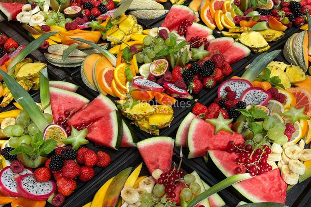 Plateaux garnis de fruits variés tels que pastèques, ananas, raisins, fraises, fruits du dragon et tranches d'agrumes.