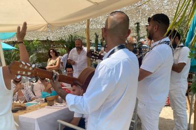Bouteilles de vin rosé sur glace devant des parasols blancs et bleus sous un ciel dégagé.