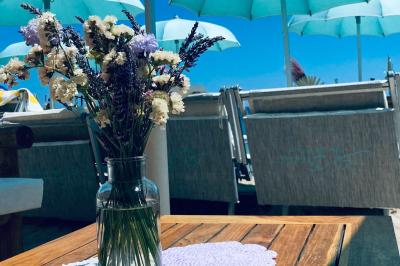 Bouteilles de vin rosé sur glace devant des parasols blancs et bleus sous un ciel dégagé.