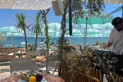 Bouteilles de vin rosé sur glace devant des parasols blancs et bleus sous un ciel dégagé.