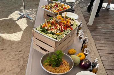 Bouteilles de vin rosé sur glace devant des parasols blancs et bleus sous un ciel dégagé.