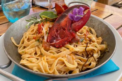 Bouteilles de vin rosé sur glace devant des parasols blancs et bleus sous un ciel dégagé.