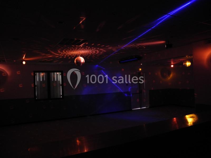 Salle sombre avec des lumières colorées et des effets de laser projetés sur les murs et le plafond.