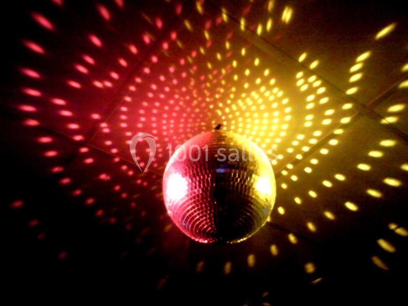 Boule à facettes suspendue reflétant des lumières jaunes et rouges sur un plafond sombre.